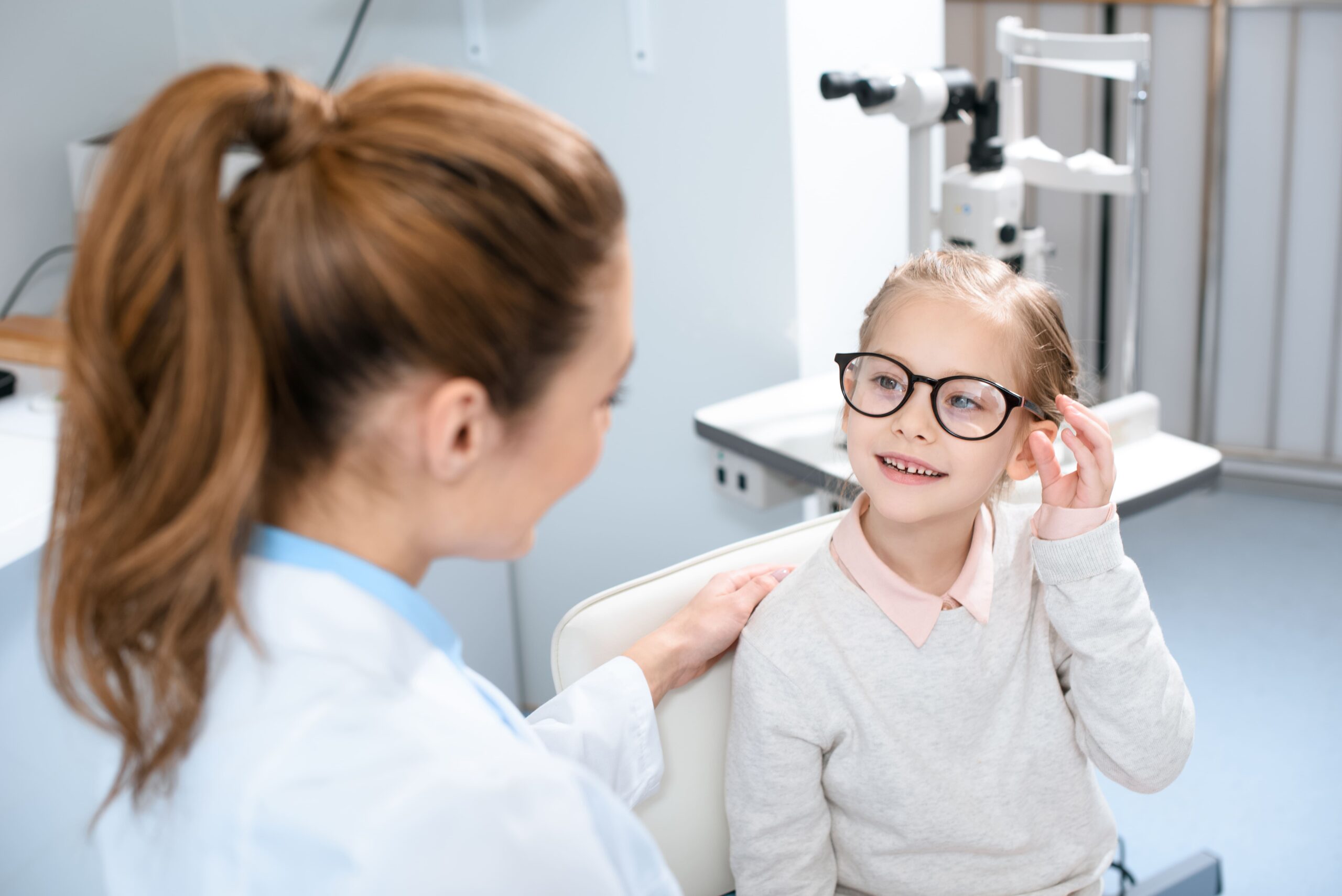 oftalmóloga con una niña que se está colocando las gafas